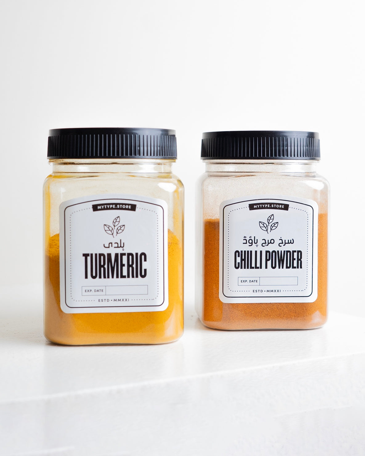 Two jars of turmeric and chili powder on a white background