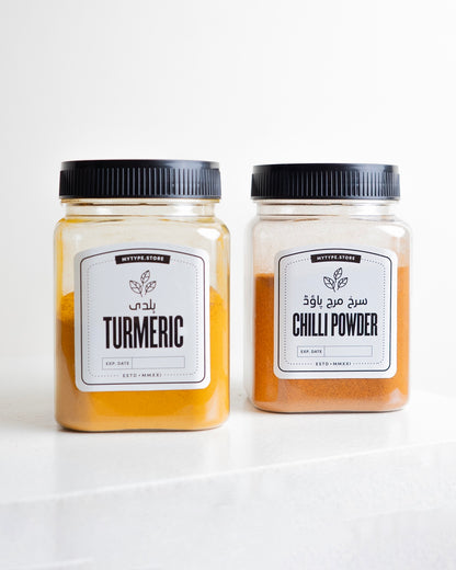 Two jars of turmeric and chili powder on a white background